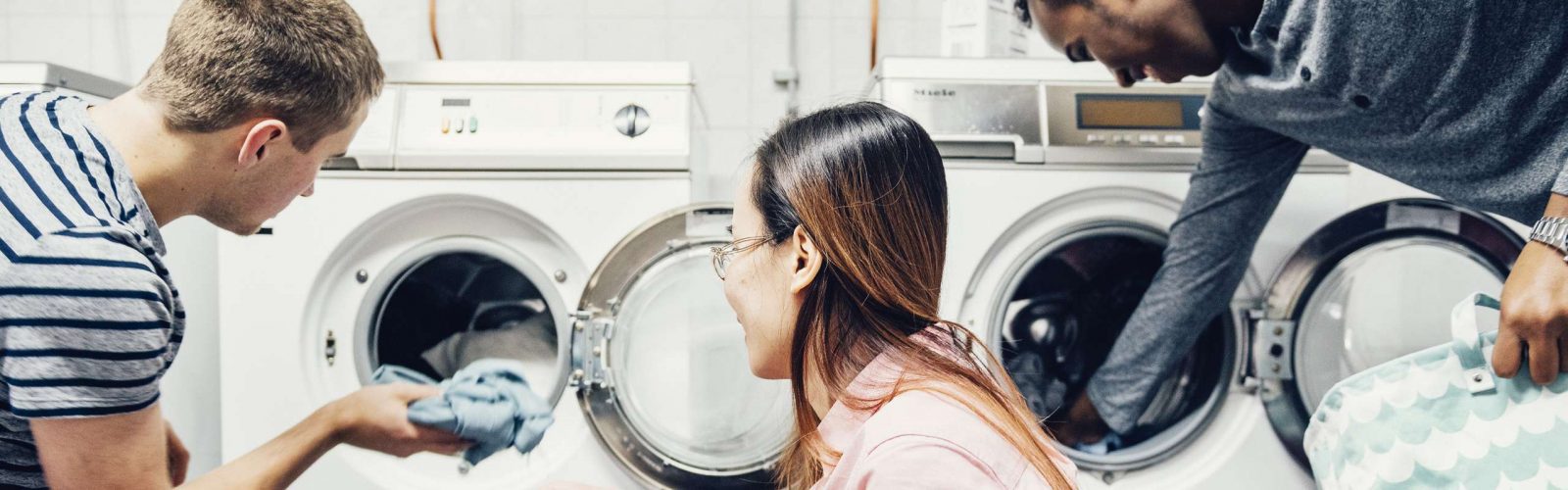 studenter stoppar in kläder i tvättmaskiner