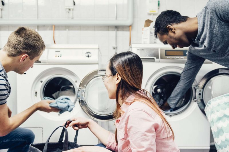 studenter stoppar in kläder i tvättmaskiner