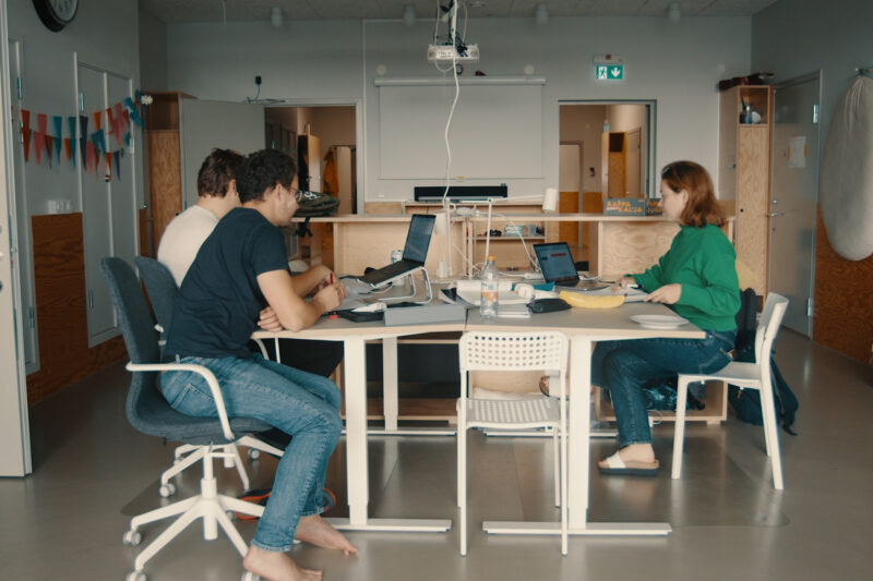 Tre studenter sitter vid ett bord och studerar