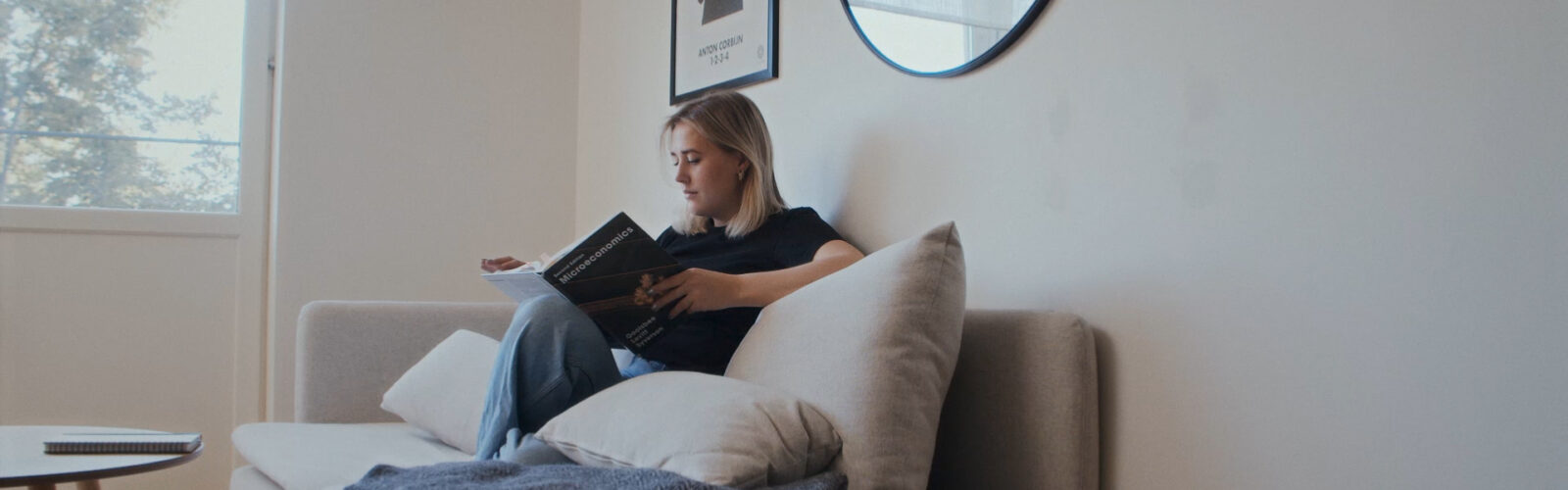 Student sitter i soffa och läser